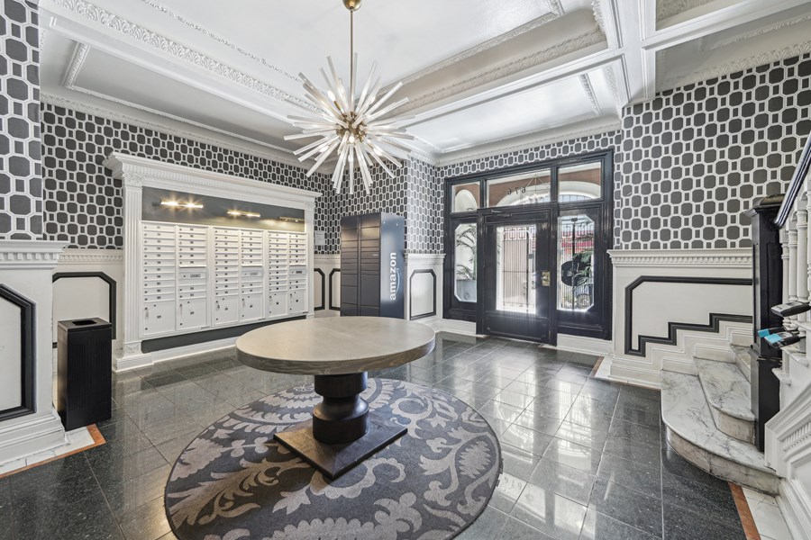 A black and white tiled foyer with a round table and a chandelier.